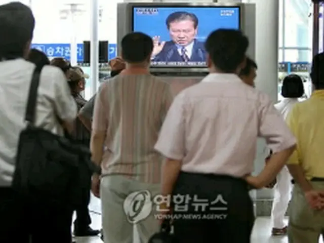 ソウル駅で金元大統領逝去のニュースに釘付けになる市民＝18日、ソウル（聯合ニュース）