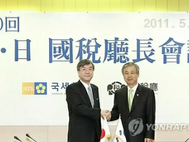 韓日税務長官会合で握手を交わす李炫東庁長（右）と川北力長官＝11日、ソウル（聯合ニュース）
