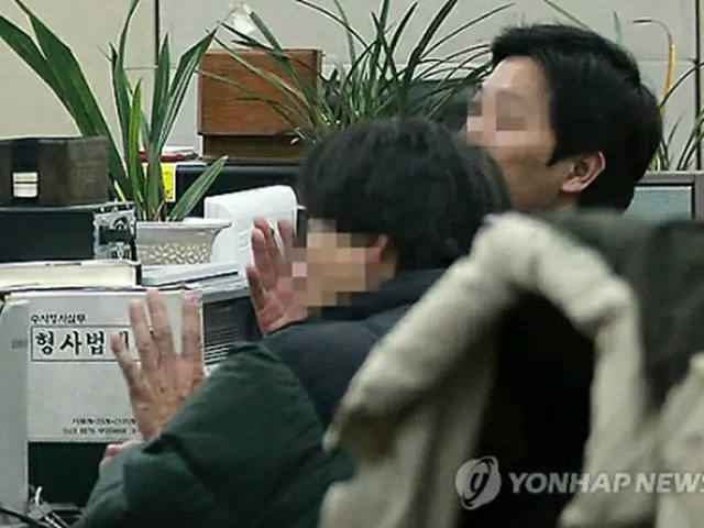 警察で調べを受けている中国人の男（左）＝（聯合ニュース）