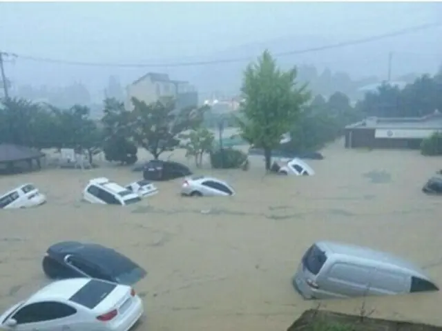 浸水した道路で水に流される車両＝25日、釜山（聯合ニュース）