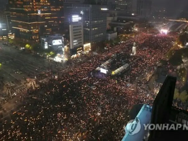 ５日、手にろうそくを持ち、光化門広場で開かれた朴大統領の退陣を求める集会に参加した市民ら＝（聯合ニュース）