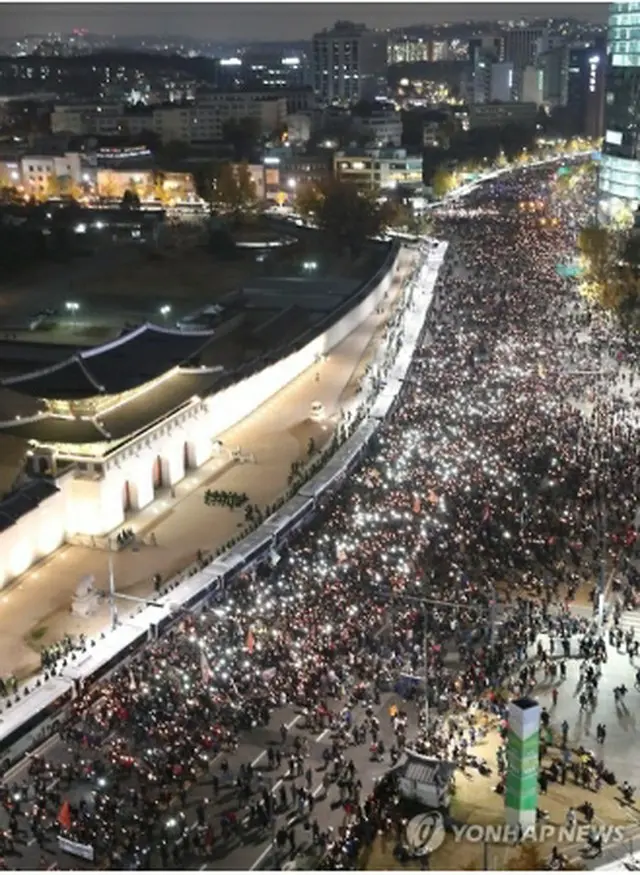 朴大統領の退陣を求め、ソウル・光化門前で行進する集会参加者＝１２日、ソウル（聯合ニュース）