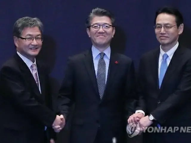 昨年１２月にソウルで開かれた会合で手を取り合う韓米日首席代表。（左から）ユン氏、金氏、金杉氏＝（聯合ニュース）