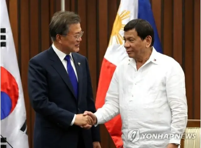 フィリピンのドゥテルテ大統領（右）と握手する文大統領＝１３日、マニラ（聯合ニュース）