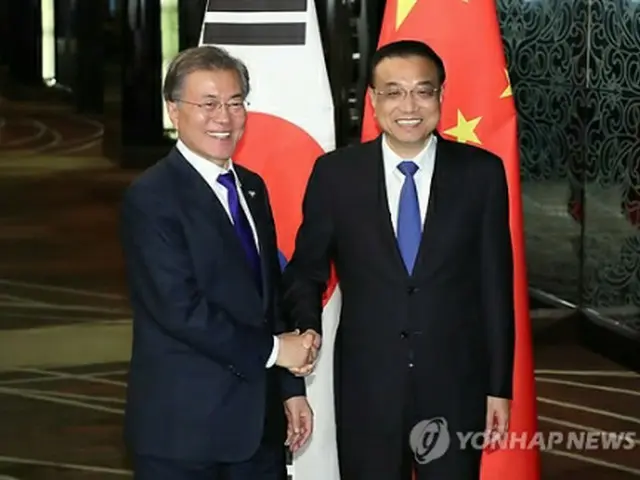 笑顔で握手を交わす文大統領と李首相＝１３日、マニラ（聯合ニュース）