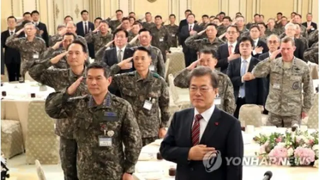 昼食会で国旗に敬礼する文大統領（手前右）と軍の指揮官ら＝８日、ソウル（聯合ニュース）