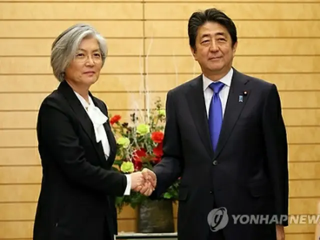 安倍首相と握手を交わす康長官＝１９日、東京（聯合ニュース）