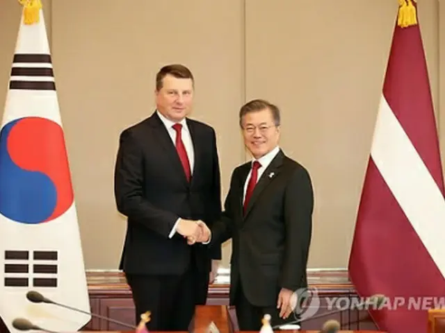 首脳会談で握手を交わす文大統領（右）とベーヨニス大統領＝１３日、ソウル（聯合ニュース）