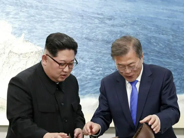 昨夜の晩餐でデザートを開封して中身をじっくり見ている北朝鮮の金正恩党委員長と韓国の文在寅大統領。（提供:news1）