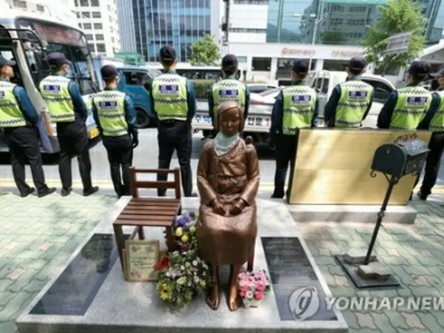 釜山の日本総領事館前に建てられている慰安婦被害者を象徴する少女像のそばで警備に当たる警官隊。市民団体は少女像の隣に労働者像を設置すると予告した＝３０日、釜山（聯合ニュース）