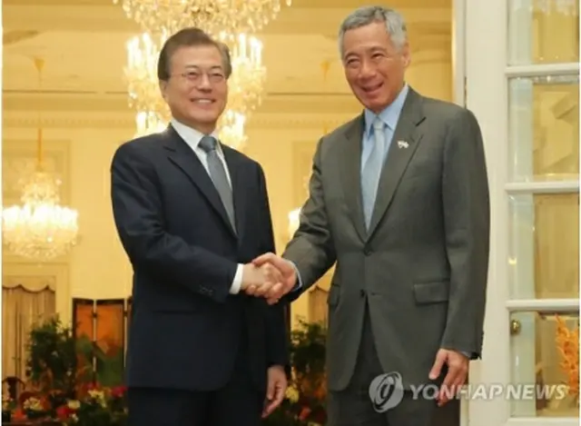 握手を交わす文大統領（左）とリー・シェンロン首相＝12日、シンガポール（聯合ニュース）