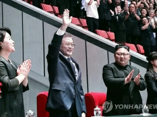マスゲームの会場で北朝鮮住民に手を振る文大統領（左から２人目）。ソウルに設置されたプレスセンターのモニターから＝１９日、ソウル（聯合ニュース）