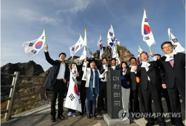 独島で韓国国旗の太極旗を振る議員ら＝２２日、独島（聯合ニュース）