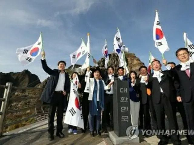 独島で韓国国旗の太極旗を振る議員ら＝２２日、独島（聯合ニュース）