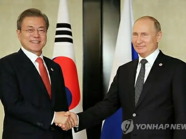 握手を交わす文大統領とプーチン大統領＝１４日、シンガポール（聯合ニュース）