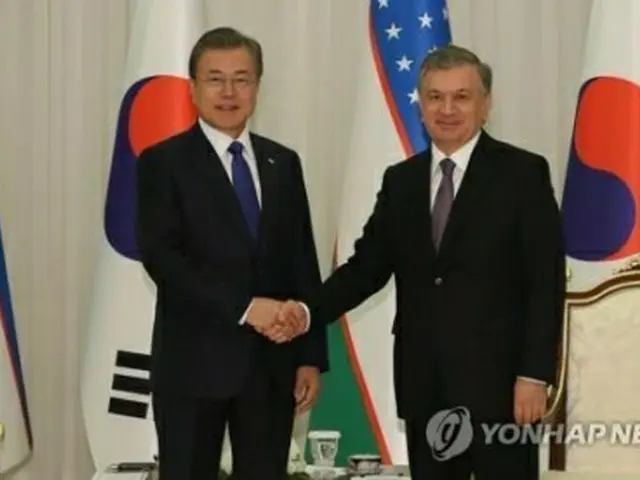 首脳会談に先立ち握手する文大統領（左）とミルジヨエフ大統領＝１９日、タシケント（聯合ニュース）