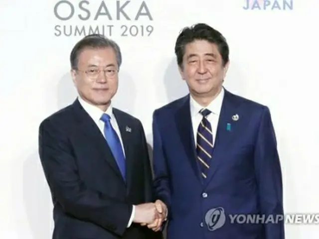 Ｇ２０サミットで握手を交わす文大統領（左）と安倍首相＝２８日、大阪（聯合ニュース）