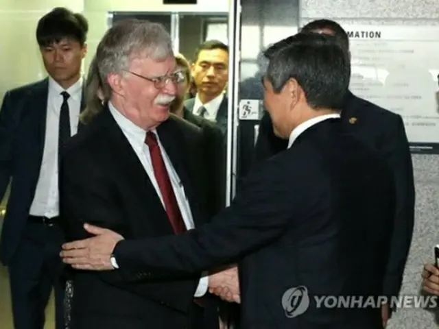 鄭氏（右）と握手するボルトン氏＝24日、ソウル（聯合ニュース）