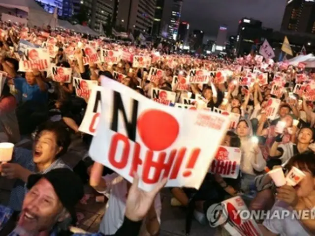 光復節の8月15日にソウルの光化門広場で開かれた集会で、「NO安倍」と書かれたプラカードを掲げる参加者ら＝（聯合ニュース）