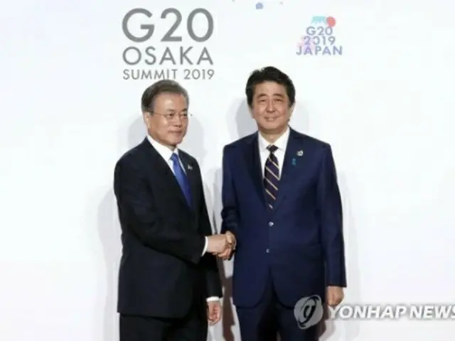 ６月に大阪で開かれた主要２０カ国・地域首脳会議（Ｇ２０サミット）で握手する文大統領（左）と安倍首相＝（聯合ニュース）