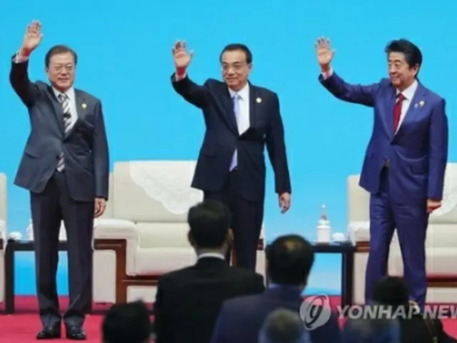 ビジネスサミットの会場で手を振る文大統領（左）、李首相（中央）、安倍首相（右）＝24日、成都（聯合ニュース）