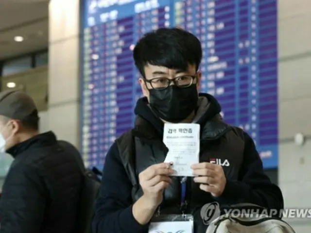 仁川国際空港で４日、中国から入国した中国人が検疫確認証を見せている＝（聯合ニュース）