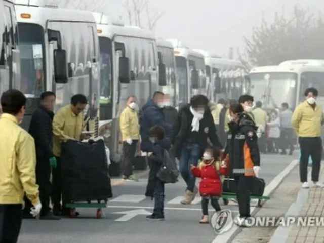 政府が用意したバスに乗り込む帰国者たち＝１５日、鎮川（聯合ニュース）
