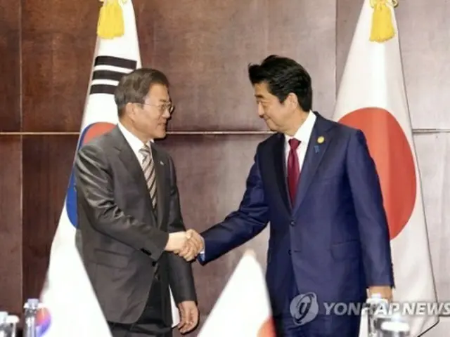 握手を交わす文大統領（左）と日本の安倍晋三首相（資料写真）＝（聯合ニュース）