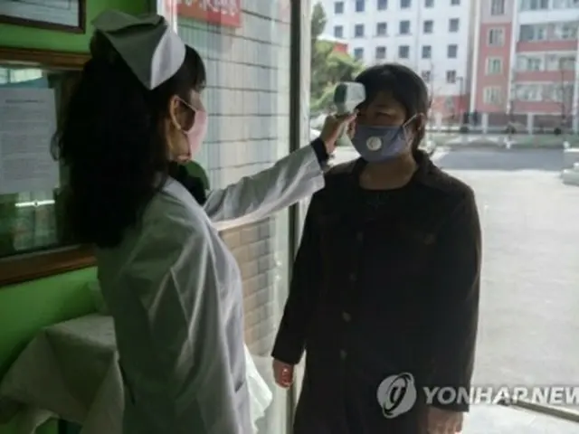北朝鮮・平壌市内の病院の入り口で、看護師が来院者の体温を確認している＝（AFP＝聯合ニュース）