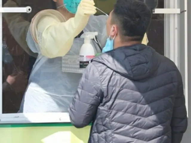 韓国・ソウルの蚕室総合運動場に設置された「ウオーキングスルー」式の新型コロナウイルス検査場で、検体を採取する医療スタッフ。ソウル市は３日から、市内在住の海外からの入国者全員に検査を実施している。入国者は空港で体温検査を行った後、感染が疑われる症状がある人は仁川空港で、症状がない人は蚕室総合運動場に設けられた検査場、または保健所で検査を受けることになる＝３日、ソウル（聯合ニュース）