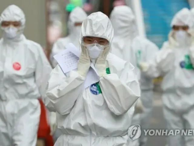 韓国南東部・大邱市の病院で、新型コロナウイルスによる感染症の治療を行う医療従事者がマスクと防護服の間にすき間がないか確認しながら病棟に向かっている＝１３日、大邱（聯合ニュース）