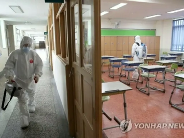 生徒の新型コロナウイルス感染が確認された釜山の高校で消毒を行う作業員＝３０日、釜山（聯合ニュース）