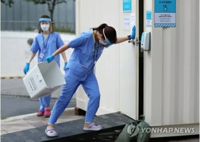 新型コロナウイルスの診療所で、台風の影響による強風に耐えながら働く医療関係者＝27日、ソウル（聯合ニュース）