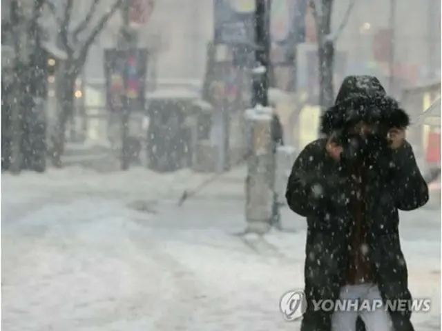 ソウルの繁華街、明洞で雪が積もった通りを歩く市民＝１２日、ソウル（聯合ニュース）