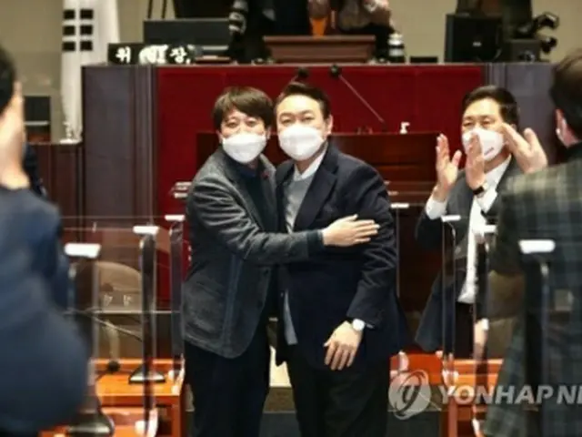 議員総会で和解した李氏(左)と尹氏(国会写真記者団)=6日、ソウル(聯合ニュース)