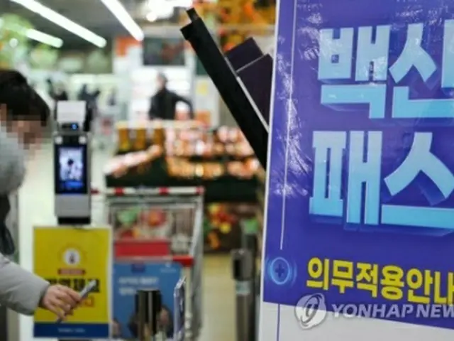 ソウル市内の大型スーパーの入り口で防疫パスを提示する来店客＝１３日、ソウル（聯合ニュース）