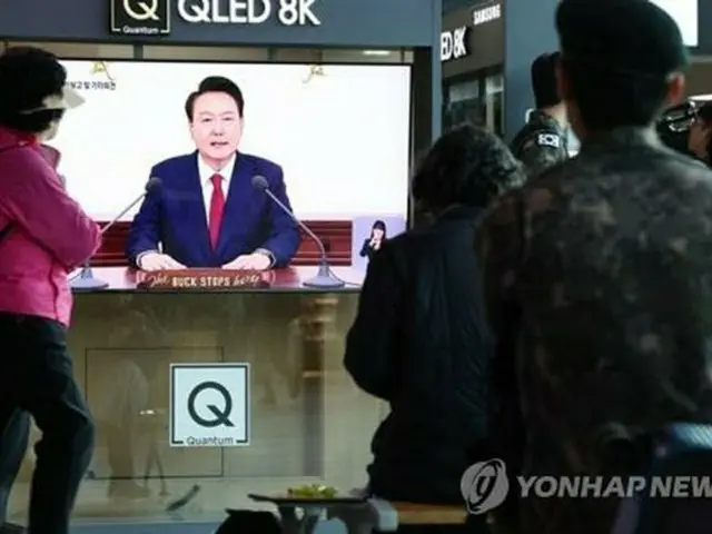ソウル駅の待合室に設置されたテレビで尹大統領の会見を見る市民たち＝９日、ソウル（聯合ニュース）