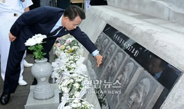 戦跡碑の裏側に刻まれた戦死者のレリーフに触れる韓首相＝29日、平沢（聯合）