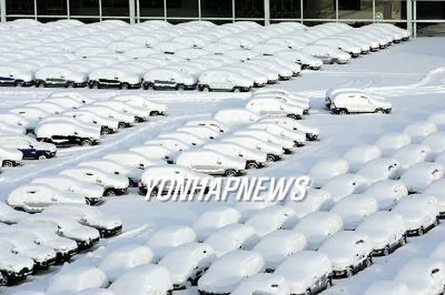 すっぽりと雪に覆われた起亜自動車光州工場の輸出用車両＝２２日、光州（聯合）