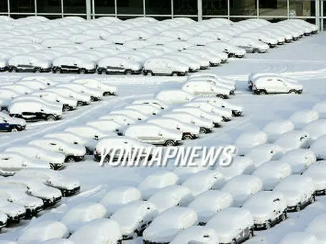 すっぽりと雪に覆われた起亜自動車光州工場の輸出用車両＝２２日、光州（聯合）
