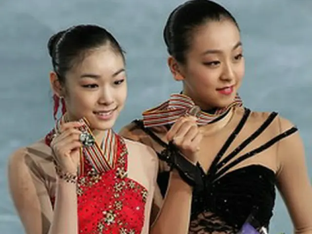 メダルを掲げてみせるキム・ヨナ（左）と3位の浅田真央＝7日、バンクーバー（聯合ニュース）