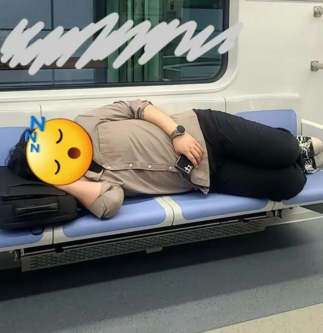 地下鉄の座席で横になって寝ている男性