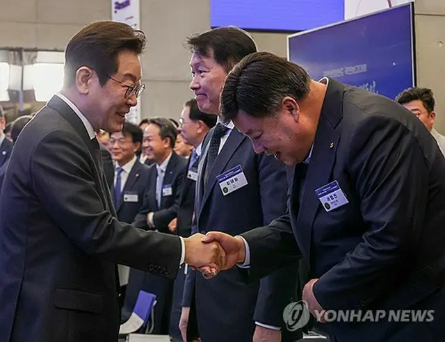 報告大会で韓国製薬大手のセルトリオンの徐廷珍（ソ・ジョンジン）会長（右）と握手する李大統領＝１０日、ソウル（聯合ニュース）