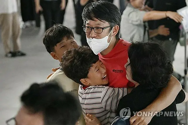 家族と抱き合って再会を喜ぶ帰国者＝１２日、仁川（聯合ニュース）