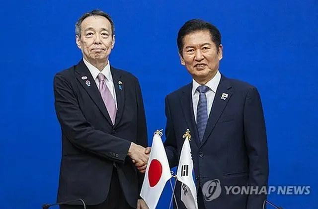 握手を交わす「共に民主党」の鄭清来代表（右）と日本の水嶋光一駐韓大使＝１５日、ソウル（聯合ニュース）