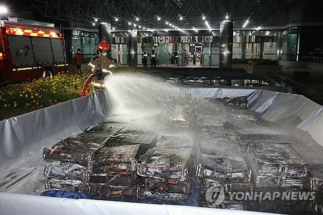 消防隊員が全焼したバッテリーに水をかけている＝２７日、大田（聯合ニュース）
