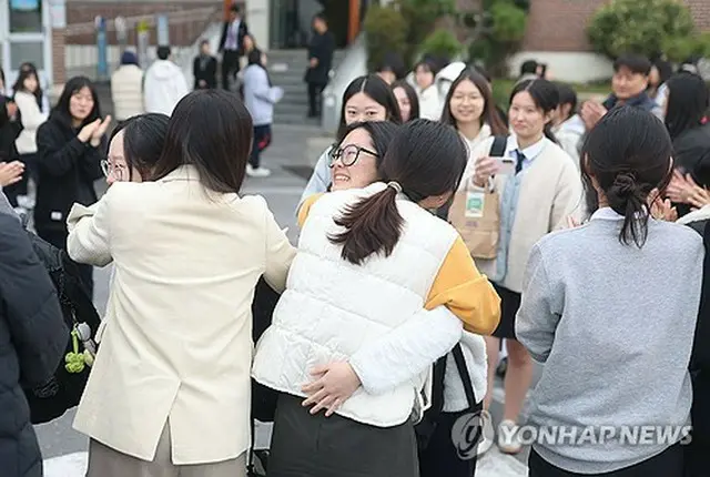 大学修学能力試験を翌日に控え、南部・昌原の女子高で教師と抱擁を交わす受験生たち＝１２日、昌原（聯合ニュース）