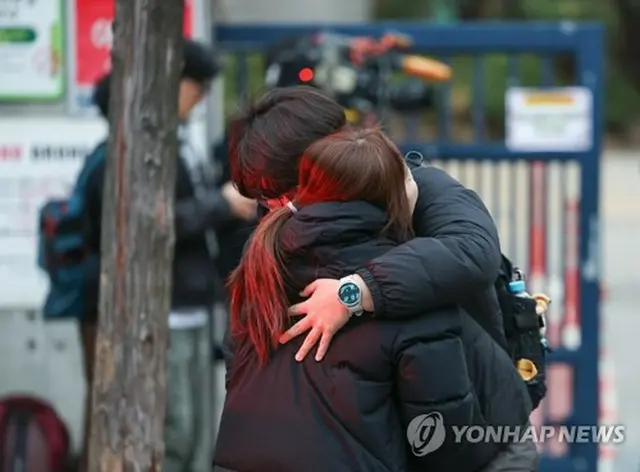 保護者と抱き合う受験生＝１３日、ソウル（聯合ニュース）