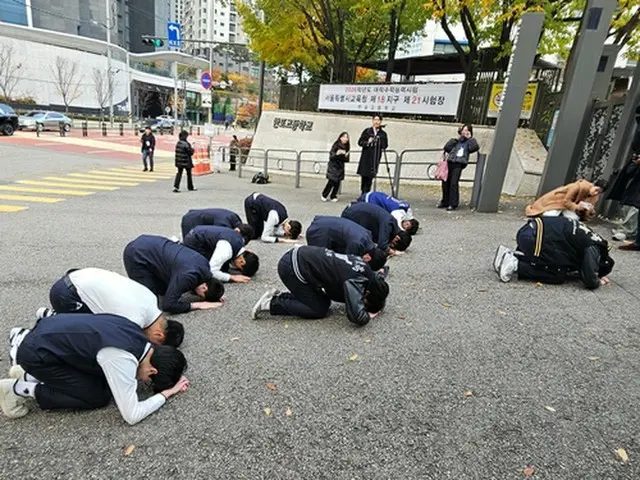 試験会場の前でクンジョル（最上級のお辞儀）をささげる下級生たち＝１３日、ソウル（聯合ニュース）