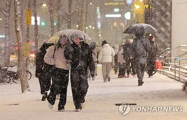 雪が降るソウル市内を歩く市民＝４日、ソウル（聯合ニュース）